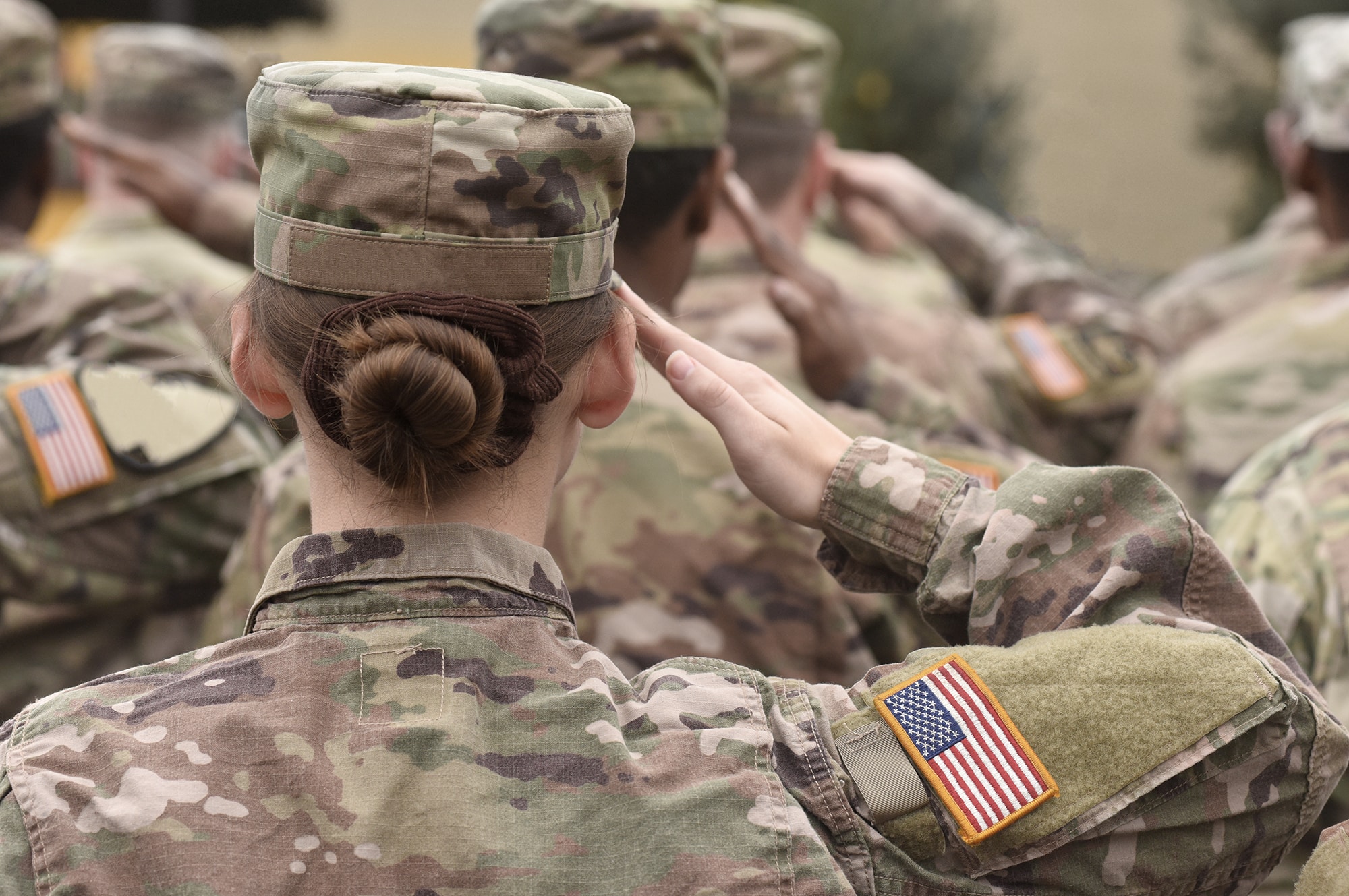 veterans saluting from behind in army green outfit with hair pulled into a bun