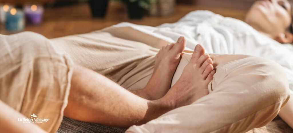 Client relaxing during a foot and leg stretch as part of a calming Thai wellness massage session.