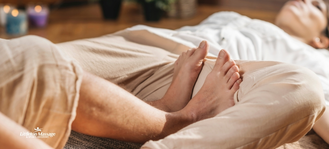 Client relaxing during a foot and leg stretch as part of a calming Thai wellness massage session.