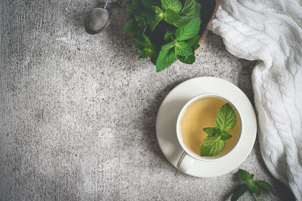 white mug of hot tea with a cozy blanket and mint leaves 