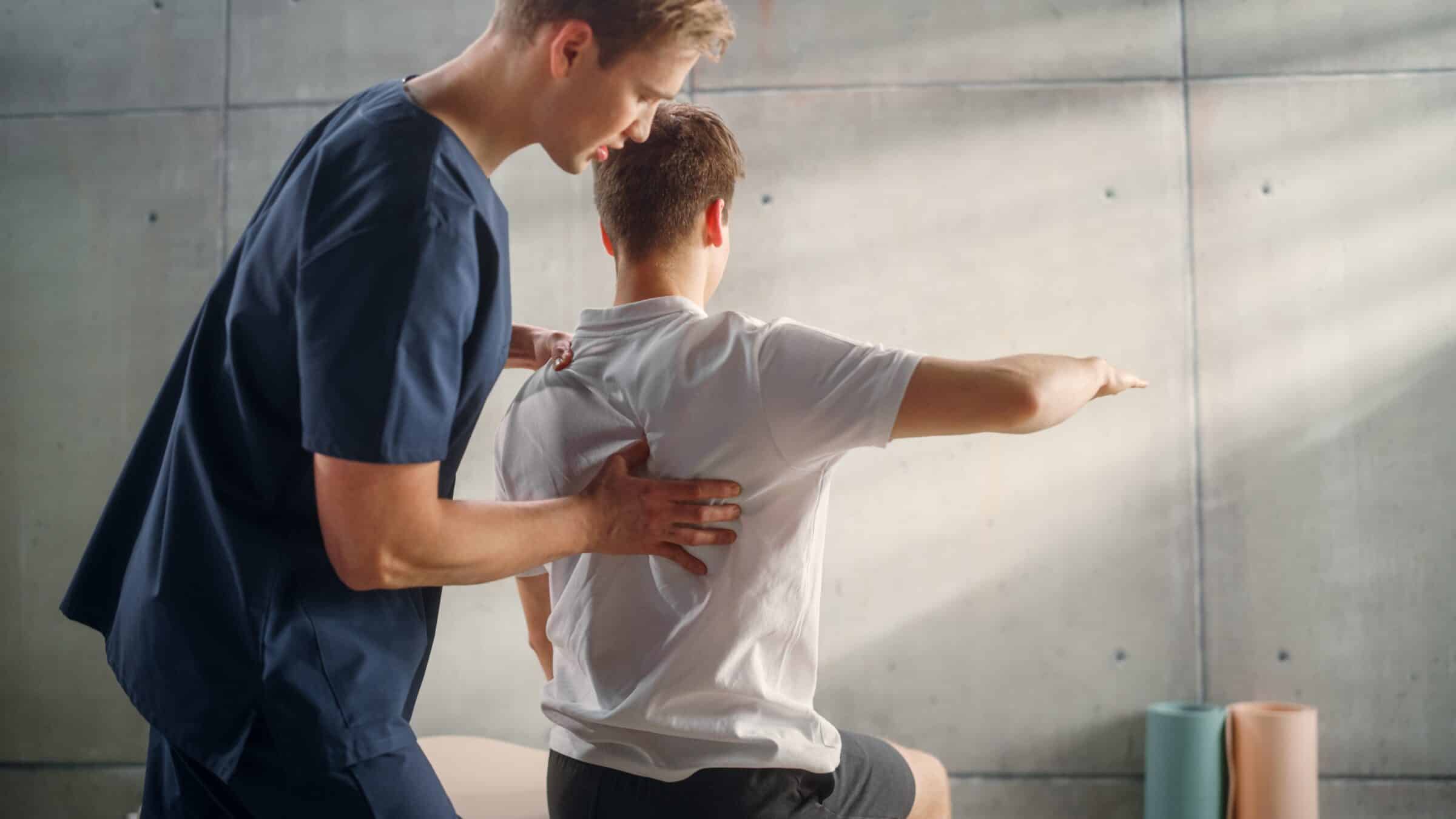 functional sports therapist assisting a patient with a stretch on a table