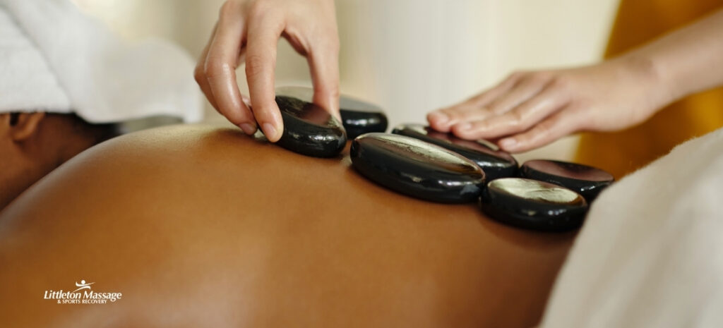 Hot stone massage in progress at Littleton Massage, illustrating heat therapy for muscle pain and the benefits of deep warmth on winter muscle stiffness.