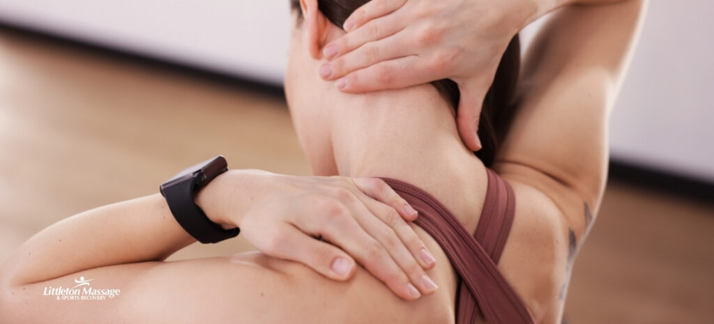Woman gripping her neck and shoulder showing how trauma in the body creates tension that myofascial release for trauma can help relieve.