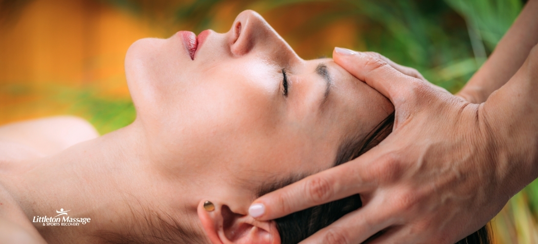 Therapist applying gentle cranial massage techniques to a relaxed woman for migraine relief at Littleton Massage & Sports Recovery