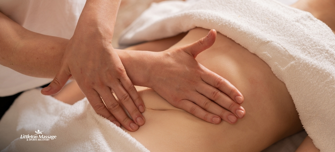 Close-up of a therapist's hands using light, gliding strokes during a lymphatic drainage massage on a client's stomach